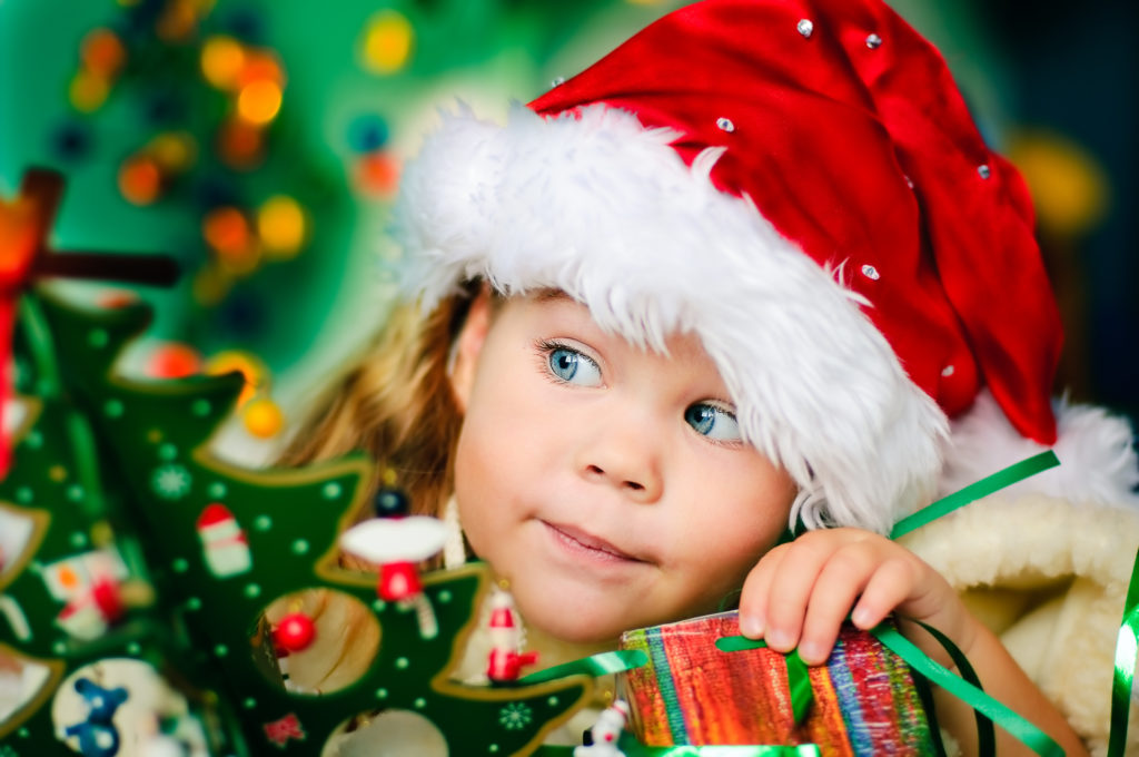 Happy small girl in santa hat with present have a christmas