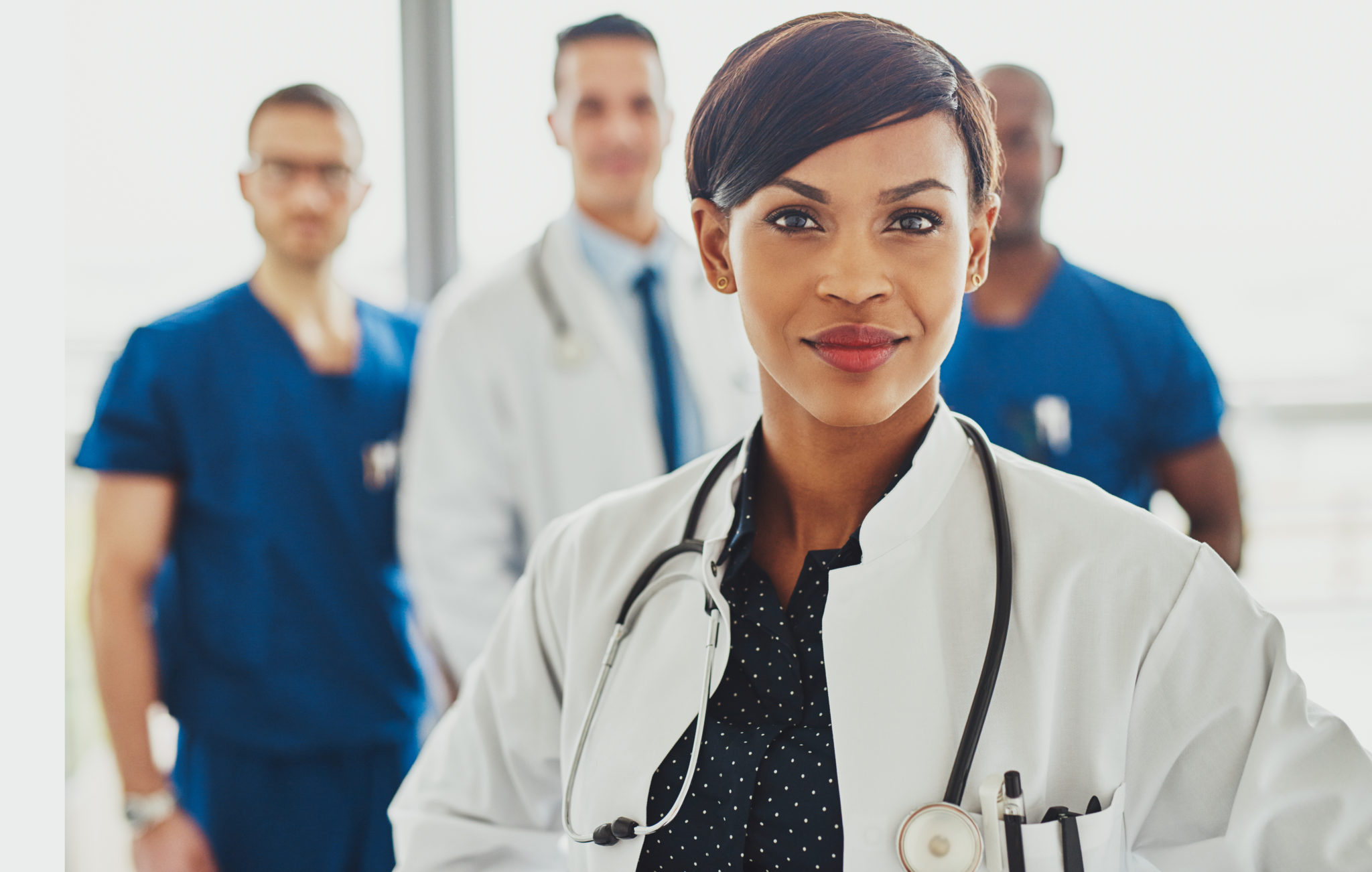 Black female doctor leading medical team at hospital, stethoscope around neck