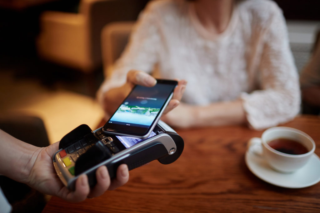Modern person paying for her tea from smartphone